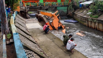 Warga melihat pos pantau Pintu Air Palmerah yang rubuh di Palmerah, Jakarta, Selasa (6/2/2024). [Suara.com/Alfian Winanto]