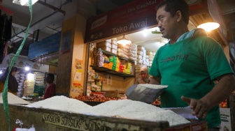 Pedagang beras melayani pembeli di pasar Cibubur, Jakarta, Senin (19/2/2024). [Suara.com/Alfian Winanto]