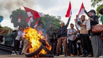 Massa yang tergabung dalam Gerakan Masyarakat Sipil Selamatkan Demokrasi Indonesia membakar ban saat menggelar aksi di depan Gedung Komisi Pemilihan Umum (KPU) RI, Jakarta, Jumat (23/2/2024). [Suara.com/Alfian Winanto]