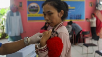 Petugas Suku Dinas Ketahanan Pangan, Kelautan dan Pertanian (Sudin KPKP) Jakarta Selatan menyuntikkan vaksin rabies ke hewan di RPTRA Ciganjur Berseri, Jakarta, Senin (26/2/2024). [Suara.com/Alfian Winanto]
