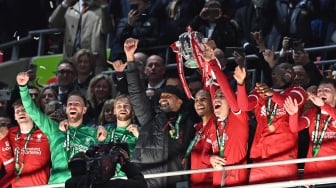 Manajer Liverpool asal Jerman Jurgen Klopp (tengah) bersama para pemain Liverpool mengangkat trofi setelah pertandingan final Carabao Cup antara Chelsea dan Liverpool di stadion Wembley, London, Inggris, Minggu (25/2/2024). [Glyn KIRK / AFP]
