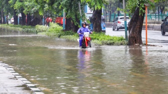 Seorang pengendara motor melintas banjir di sekitar Cempaka Putih, Jakarta, Kamis (29/2/2024). [Suara.com/Alfian Winanto]