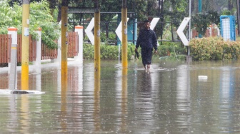 Warga berjalan melewati banjir di sekitar Cempaka Putih, Jakarta, Kamis (29/2/2024). [Suara.com/Alfian Winanto]