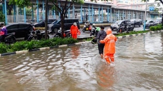 Warga berjalan melewati banjir di sekitar Cempaka Putih, Jakarta, Kamis (29/2/2024). [Suara.com/Alfian Winanto]