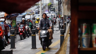 Pengendara sepeda motor melintas di trotoar kawasan Matraman, Jakarta, Selasa (5/3/2024). [Suara.com/Alfian Winanto]