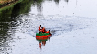 Petugas UPS Badan Air Dinas Lingkungan Hidup DKI Jakarta menaiki perahu motor berbahan botol plastik bekas di Kanal Banjir Timur, Duren Sawit, Jakarta, Rabu (6/3/2024). [Suara.com/Alfian Winanto]