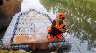 Petugas UPS Badan Air Dinas Lingkungan Hidup DKI Jakarta mengoperasikan perahu motor berbahan botol plastik bekas di Kanal Banjir Timur, Duren Sawit, Jakarta, Rabu (6/3/2024). [Suara.com/Alfian Winanto]