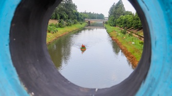 Petugas UPS Badan Air Dinas Lingkungan Hidup DKI Jakarta menaiki perahu motor berbahan botol plastik bekas di Kanal Banjir Timur, Duren Sawit, Jakarta, Rabu (6/3/2024). [Suara.com/Alfian Winanto]