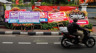 Pengendara melintas didepan karangan bunga menolak kecurangan pemilu di depan Kantor DPP PDI Perjuangan di Jakarta, Jumat (8/3/2024). [Suara.com/Alfian Winanto]