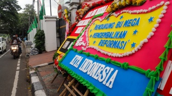 Pengendara melintas didepan karangan bunga menolak kecurangan pemilu di depan Kantor DPP PDI Perjuangan di Jakarta, Jumat (8/3/2024). [Suara.com/Alfian Winanto]