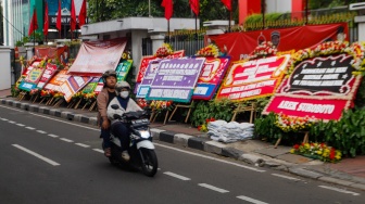 Pengendara melintas didepan karangan bunga menolak kecurangan pemilu di depan Kantor DPP PDI Perjuangan di Jakarta, Jumat (8/3/2024). [Suara.com/Alfian Winanto]