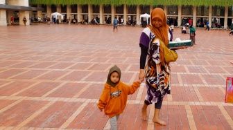 Warga membawa makanan berbuka puasa di Masjid Istiqlal, Jakarta, Selasa (12/3/2024). [Suara.com/Alfian Winanto]