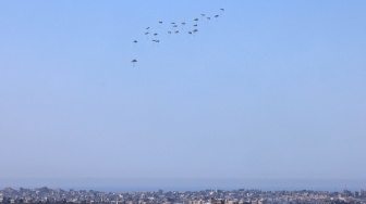 Gambar yang diambil dari perbatasan selatan Israel dengan Jalur Gaza ini menunjukkan bantuan kemanusiaan dijatuhkan dari udara di wilayah Palestina pada Selasa (12/3/2024).  [Menahem KAHANA/AFP] 