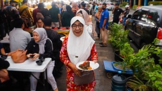 Pengunjung membawa menu berbuka puasa di Sentra kuliner Nasi Kapau di Jalan Kramat Raya, Senen, Jakarta, Kamis (14/3/2024). [Suara.com/Alfian Winanto]