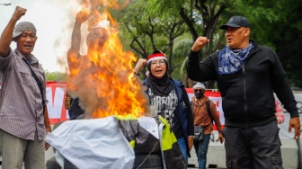 Massa yang tergabung dalam Gerakan Masyarakat Sipil Selamatkan Demokrasi Indonesia membakar ban saat menggelar aksi di depan Gedung Komisi Pemilihan Umum (KPU) RI, Jakarta,  Senin (18/3/2024). [Suara.com/Alfian Winanto]