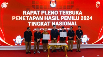 Ketua KPU Hasyim Asy'ari (tengah) bersama para anggota KPU menunjukkan Berita Acara Penetapan Hasil Pemilu 2024 yang sudah ditandatangani saat Rapat Pleno Terbuka Penetapan Hasil Pemilu 2024 Tingkat Nasional di Kantor KPU RI, Jakarta, Rabu (20/3/2024). [Suara.com/Alfian Winanto]