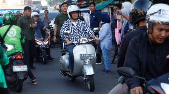 Capres nomor urut satu, Anies Baswedan menyapa warga saat mengendarai Vespa usai membeli Takjil untuk berbuka puasa di Pasar Takjil Benhil, Jakarta, Rabu (20/3/2024). [Suara.com/Alfian Winanto]