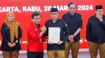 Ketua KPU Hasyim Asy'ari (tengah) menyerahkan Berita Acara Penetapan Hasil Pemilu 2024 kepada saksi Paslon Capres-Cawapres nomor urut tiga, saat Rapat Pleno Terbuka Penetapan Hasil Pemilu 2024 Tingkat Nasional di Kantor KPU RI, Jakarta, Rabu (20/3/2024). [Suara.com/Alfian Winanto]