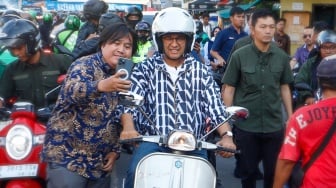 Capres nomor urut satu, Anies Baswedan berswafoto dengan warga saat mengendarai Vespa usai membeli Takjil untuk berbuka puasa di Pasar Takjil Benhil, Jakarta, Rabu (20/3/2024). [Suara.com/Alfian Winanto]