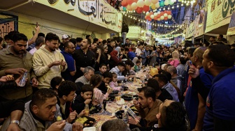 Umat ​​Muslim Mesir berkumpul di jalan-jalan yang dipenuhi meja panjang untuk berbuka puasa bersama dalam jamuan "buka puasa" massal di Ezbet Hamada, Kairo, Mesir, Senin (25/3/2024). [Khaled DESOUKI / AFP]
