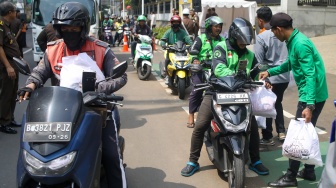 Petugas membagikan paket bantuan bahan pangan di depan Gedung Kejaksaan Agung RI, Jakarta, Senin (1/4/2024). [Suara.com/Alfian Winanto]