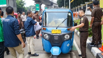 Petugas membagikan paket bantuan bahan pangan di depan Gedung Kejaksaan Agung RI, Jakarta, Senin (1/4/2024). [Suara.com/Alfian Winanto]