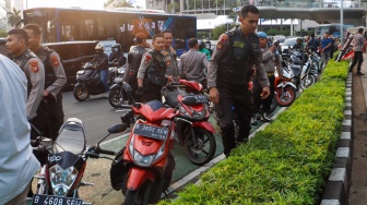 Petugas mengamankan anak-anak saat Razia konvoi kendaraan bermotor di Bundaran HI, Jakarta, Selasa (2/4/2024). [Suara.com/Alfian Winanto]