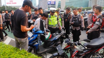 Petugas memeriksa kendaraan saat Razia konvoi kendaraan bermotor di Bundaran HI, Jakarta, Selasa (2/4/2024). [Suara.com/Alfian Winanto]