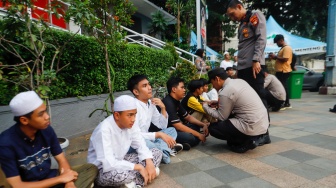 Petugas mendata identitas anak-anak saat Razia konvoi kendaraan bermotor di Bundaran HI, Jakarta, Selasa (2/4/2024). [Suara.com/Alfian Winanto]