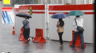 Warga berjalan menggunakan payung saat turun hujan di Kawasan Dukuh Atas, Jakarta, Rabu (3/4/2024). [Suara.com/Alfian Winanto]