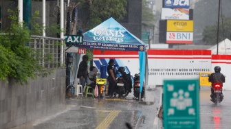 Warga berteduh saat turun hujan di Kawasan Dukuh Atas, Jakarta, Rabu (3/4/2024). [Suara.com/Alfian Winanto]