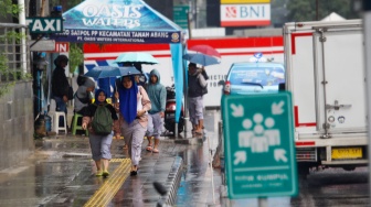 Warga berjalan menggunakan payung saat turun hujan di Kawasan Dukuh Atas, Jakarta, Rabu (3/4/2024). [Suara.com/Alfian Winanto]