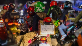 Kertas berisi pesan - pesan terpasang di belakang kendaraan pemudik bersepeda motor yang melintas di Jalan Inspeksi Kalimalang, Jakarta, Sabtu (6/4/2024). [Suara.com/Alfian Winanto]