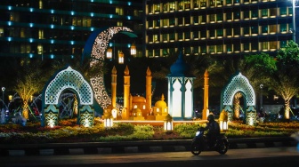 Sejumlah kendaraan melintas di depan dekorasi lebaran di kawasan Bundaran Hotel Indonesia, Jakarta, Senin (8/4/2024). [Suara.com/Alfian Winanto]