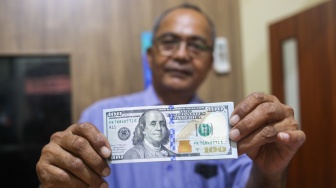 Petugas menunjukan uang dollar AS di Money Changer, Jakarta, Rabu (17/4/2024). [Suara.com/Alfian Winanto]