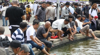 Massa mengambil air wudhu untuk salat jumat berjamaah saat aksi tolak pemilu curang di Patung Kuda, Jakarta, Jumat (19/4/2024). [Suara.com/Alfian Winanto]