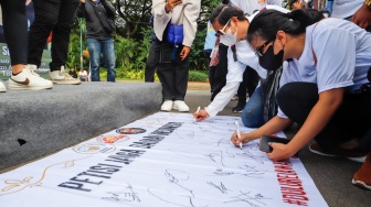 Massa relawan menandatangani Petisi Jaga Damai Indonesia di Kawasan Patung Kuda, Jakarta, Selasa (23/4/2024). [Suara.com/Alfian Winanto]