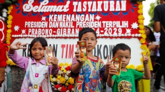 Anak-anak menunjukan susu gratis yang dibagikan di wilayah Menteng Wadas Timur, Jakarta, Selasa (30/4/2024). [Suara.com/Alfian Winanto]