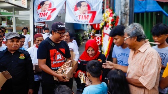 Relawan Jokowi membagikan susu kepada anak-anak di wilayah Menteng Wadas Timur, Jakarta, Selasa (30/4/2024). [Suara.com/Alfian Winanto]