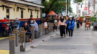 Warga berjalan melewati kawasan Transport Hub Dukuh Atas, Jakarta, Selasa (30/4/2024). [Suara.com/Alfian Winanto]