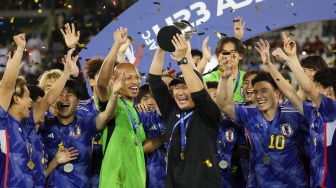Pelatih Jepang Go Oiwa (kedua kanan) selebrasi dan mengangkat trofi bersama para pemain setelah memenangkan pertandingan final Piala Asia U23 2024 antara Jepang melawan Uzbekistan di Stadion Jassim Bin Hamad, Doha, Qatar, Jumat (3/5/2024). [KARIM JAAFAR / AFP]