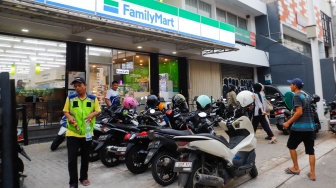 Aktivitas seorang juru parkir memarkirkan kendaraan di salah satu minimarket di kawasan Jakarta, Kamis (9/5/2024). [Suara.com/Alfian Winanto]