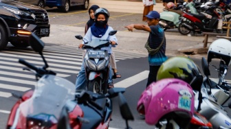 Aktivitas seorang juru parkir memarkirkan kendaraan di salah satu minimarket di kawasan Jakarta, Kamis (9/5/2024). [Suara.com/Alfian Winanto]