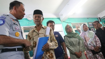 Petugas memberikan santunan secara simbolis kepada ahli waris korban kecelakaan bus di SMK Lingga Kencana, Depok, Jawa Barat, Senin (13/5/2024). [Suara.com/Alfian Winanto]