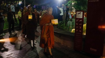 Para Bhikkhu berjalan sambil membawa lentera saat prosesi Walking Meditation di Taman Mini Indonesia Indah, Jakarta, Selasa (14/5/2024). [Suara.com/Alfian Winanto]