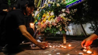 Warga menyalakan lilin di tengah karangan bunga yang terpajang di depan Kantor Kedutaan Besar Iran, Jakarta, Senin (20/5/2024). [Suara.com/Alfian Winanto]