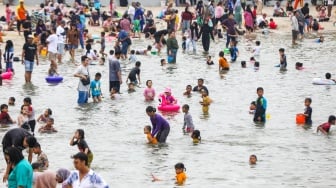 Pengunjung berwisata di Pantai Lagoon, Ancol Taman Impian, Jakarta, Minggu (26/5/2024). [Suara.com/Alfian Winanto]