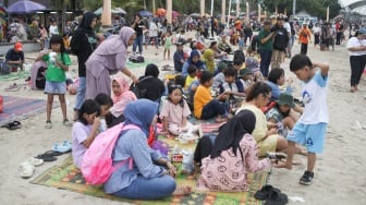 Pengunjung berwisata di Pantai Lagoon, Ancol Taman Impian, Jakarta, Minggu (26/5/2024). [Suara.com/Alfian Winanto]