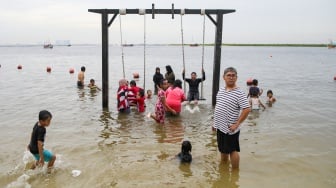 Pengunjung berwisata di Pantai Lagoon, Ancol Taman Impian, Jakarta, Minggu (26/5/2024). [Suara.com/Alfian Winanto]