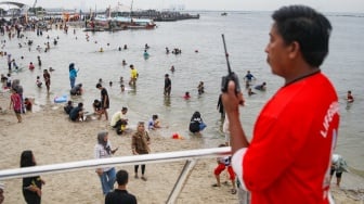 Pengunjung berwisata di Pantai Lagoon, Ancol Taman Impian, Jakarta, Minggu (26/5/2024). [Suara.com/Alfian Winanto]